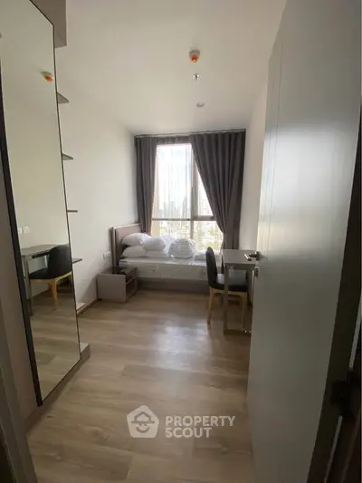 Cozy bedroom with large window and modern furnishings in a stylish apartment.