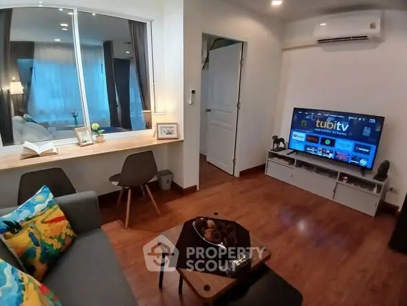 Cozy living room with modern decor, featuring a wall-mounted TV and stylish furniture.