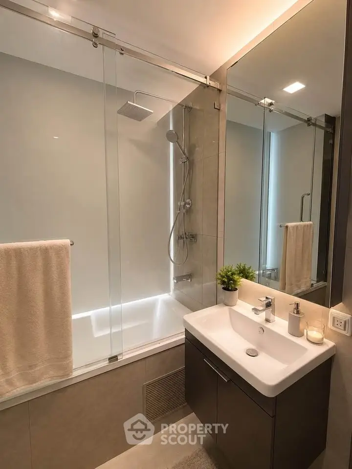 Modern bathroom with glass shower and sleek vanity in contemporary apartment.