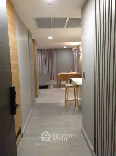 Modern apartment hallway leading to a cozy living area with stylish decor and neutral tones.