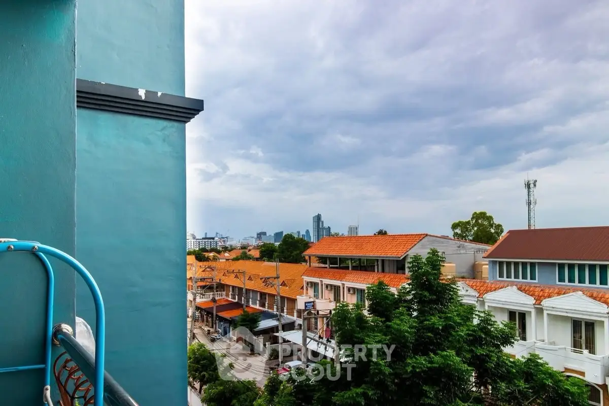 Charming urban view from a balcony overlooking vibrant cityscape and lush greenery, perfect for city living.