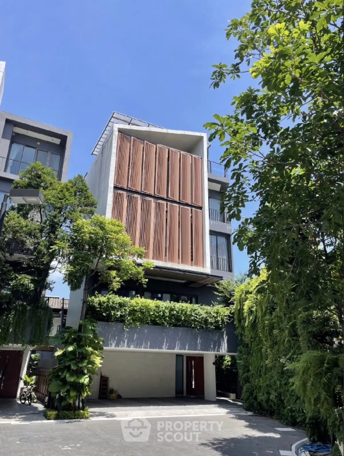 Modern multi-story building with lush greenery and unique architectural design.