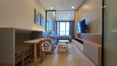 Modern studio apartment with open layout and stylish decor, featuring a cozy living area and large windows.