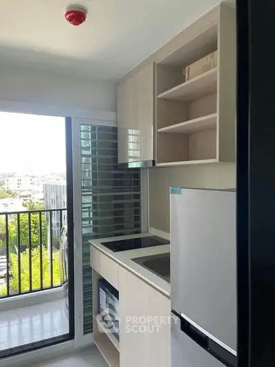 Modern kitchen with sleek appliances and balcony view in a stylish apartment.
