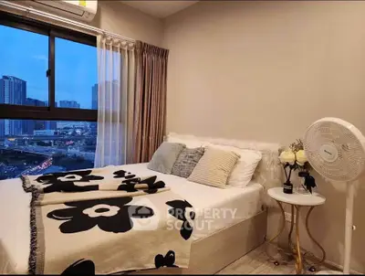 Cozy bedroom with city view, featuring modern decor and large window for natural light.