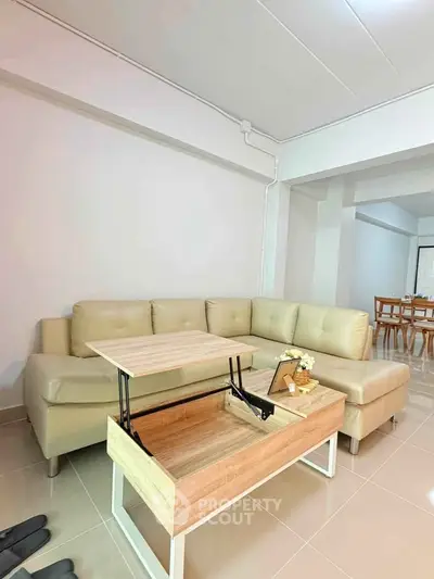 Modern living room with beige sectional sofa and multifunctional coffee table in open layout.