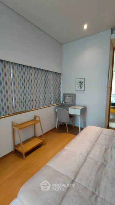 Cozy bedroom with modern decor and study desk, featuring stylish patterned curtains.