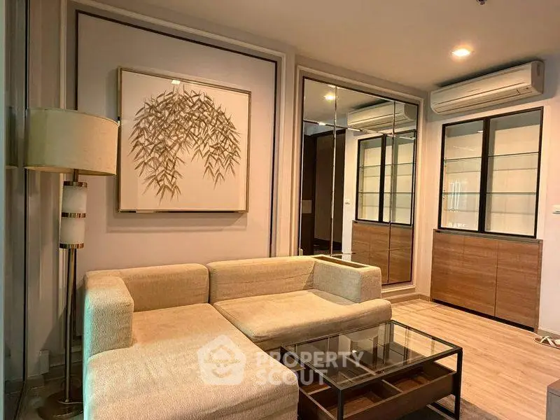 Modern living room with beige sectional sofa, glass coffee table, and mirrored cabinets.