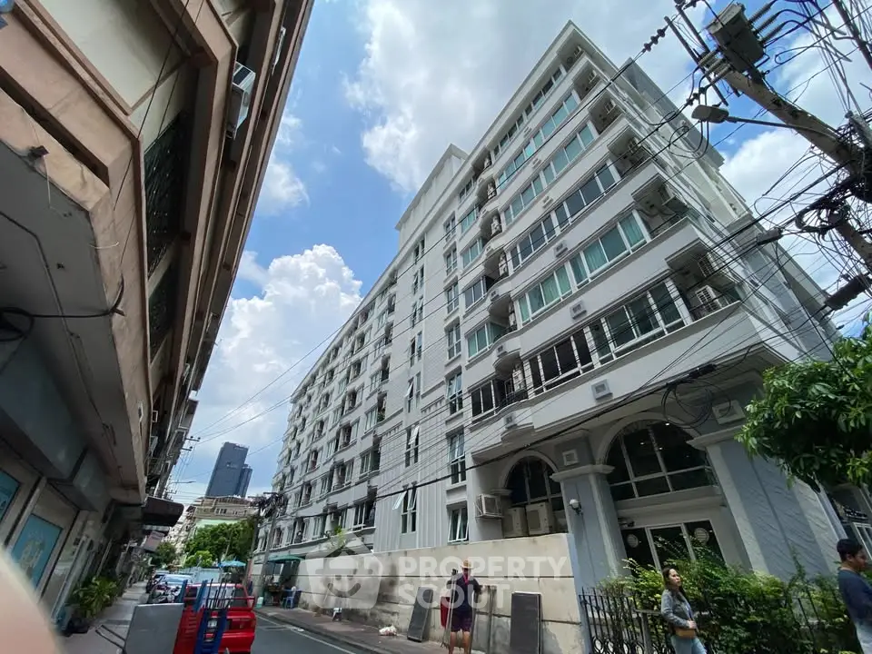 Modern multi-story residential building with street view and clear blue sky.