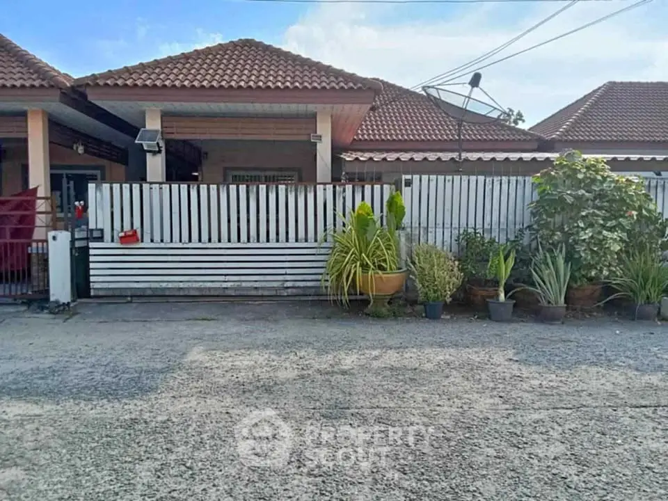 Charming single-story house with tiled roof and lush garden, perfect for family living.