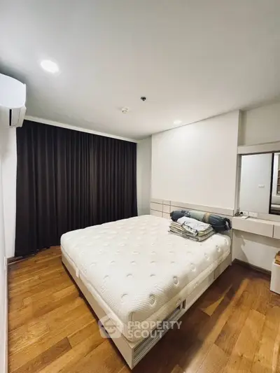 Spacious bedroom with modern design and wooden flooring, featuring a comfortable bed and ample natural light.