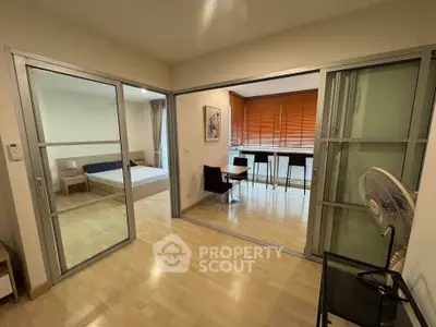 Spacious modern apartment with sliding glass doors and wooden flooring, featuring a cozy bedroom and stylish dining area.