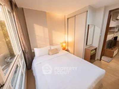 Cozy bedroom with natural light, modern furnishings, and a large window offering a serene view.