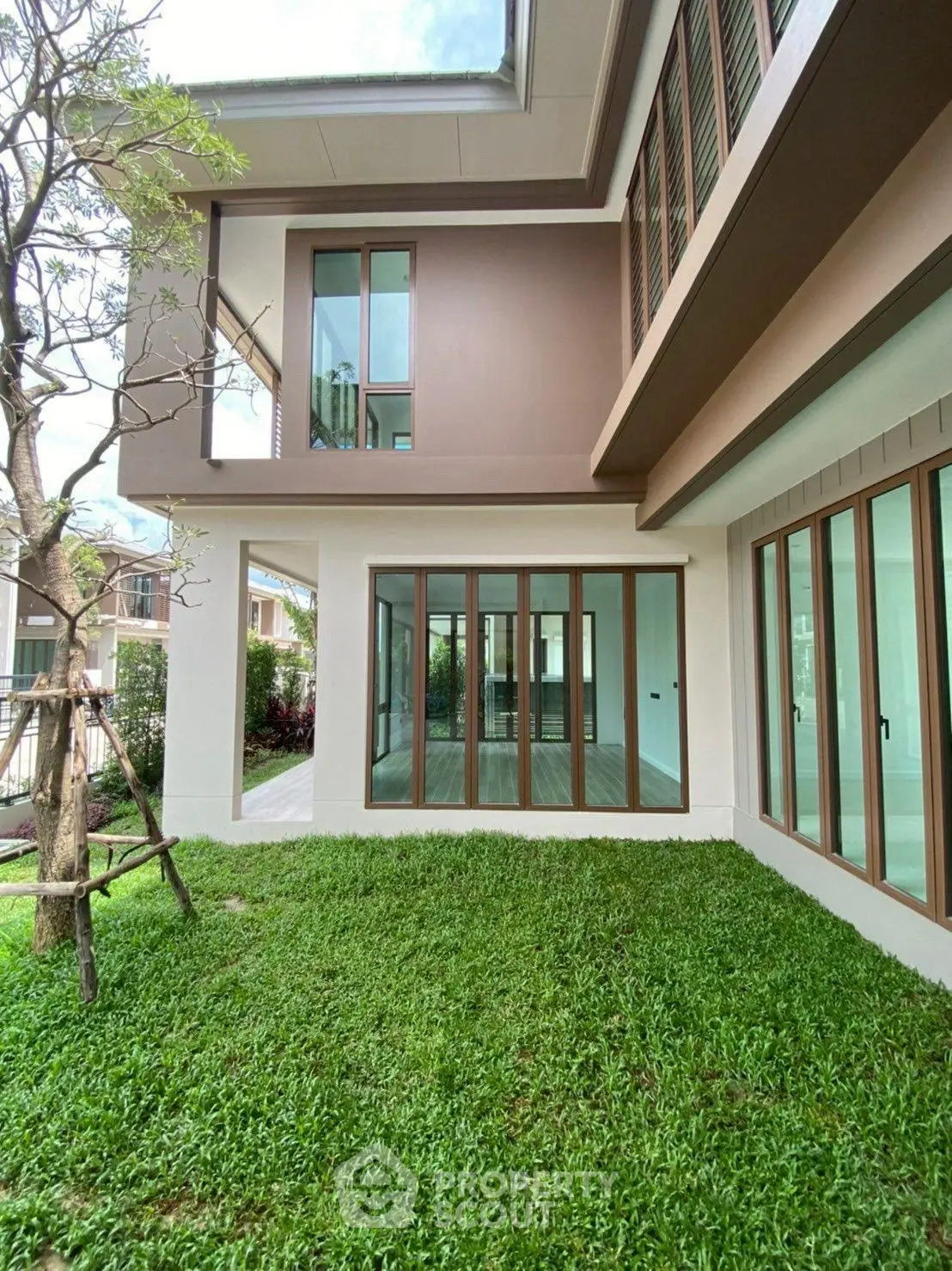 Modern two-story house with large windows and lush green lawn