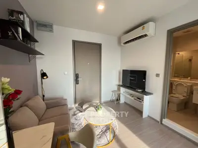 Modern living room with cozy sofa, wall-mounted TV, and adjacent bathroom in a stylish apartment.