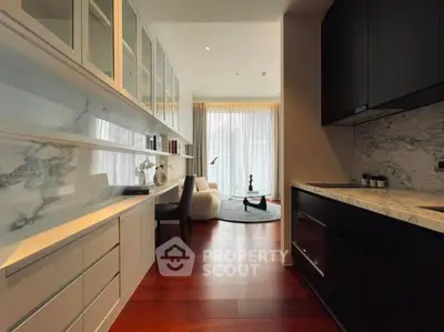 Modern open-layout kitchen with sleek cabinetry and cozy living area, featuring elegant marble accents and warm wood flooring.