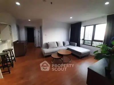 Spacious living room with modern furniture and large window offering city views.