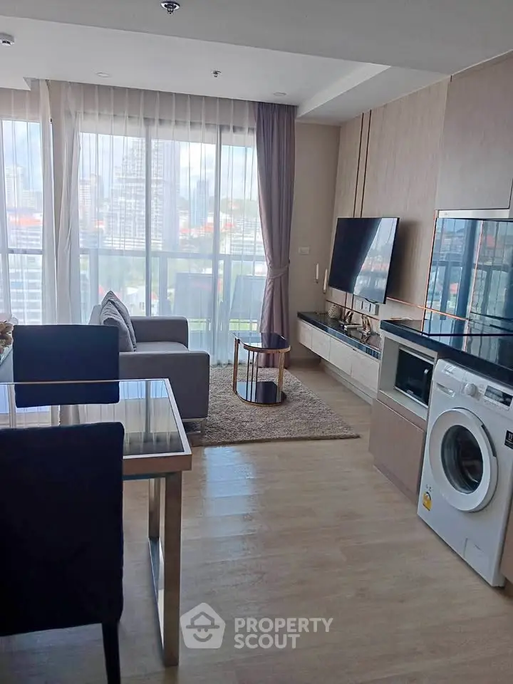 Modern living room with city view, featuring sleek furniture and in-unit washing machine.