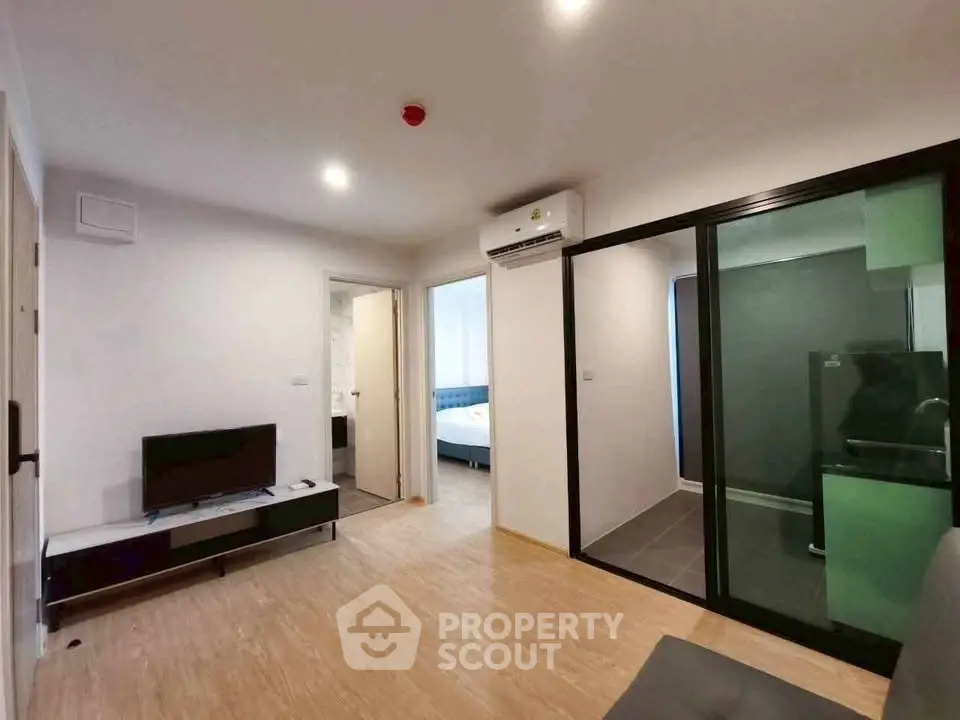 Modern living room with sleek design and glass partition, featuring a cozy bedroom view.