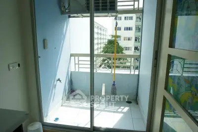 Cozy balcony with sliding glass doors and urban view, perfect for relaxation.