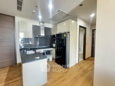 Modern kitchen with sleek appliances and wooden flooring in a stylish apartment.