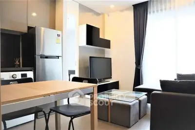 Modern living room with sleek furniture and natural light, featuring a stylish kitchen area and cozy seating.
