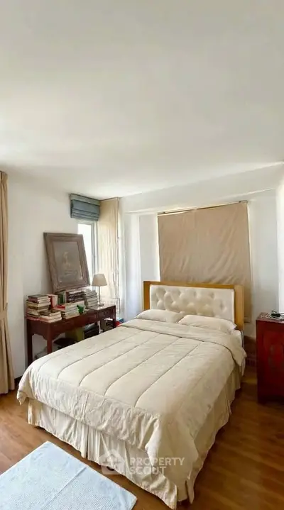 Cozy bedroom with elegant decor and natural light, featuring a plush bed and wooden flooring.