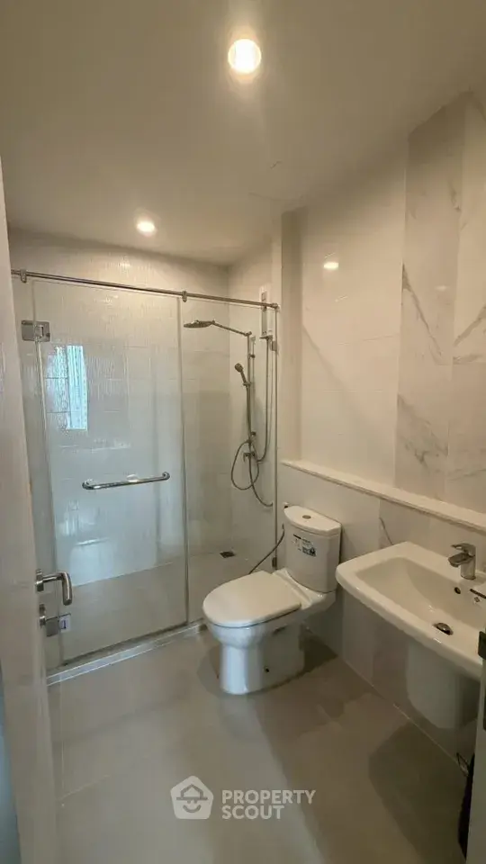 Modern bathroom with glass shower enclosure and sleek fixtures.
