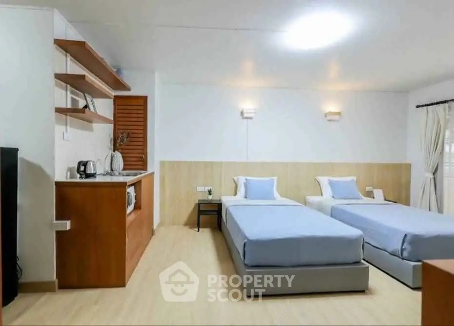 Modern bedroom with twin beds and kitchenette, ideal for cozy living.