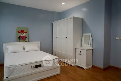 Charming bedroom with white furniture and wooden flooring, perfect for cozy living.