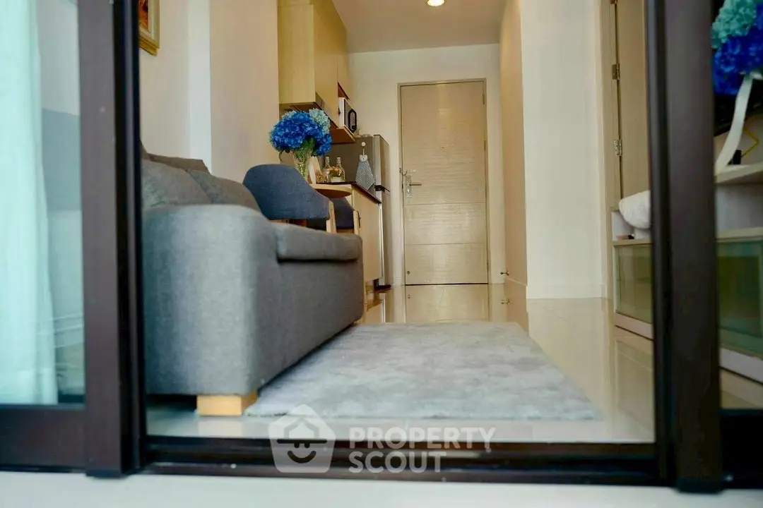 Modern living room with cozy gray sofa and stylish decor in a compact apartment setting.