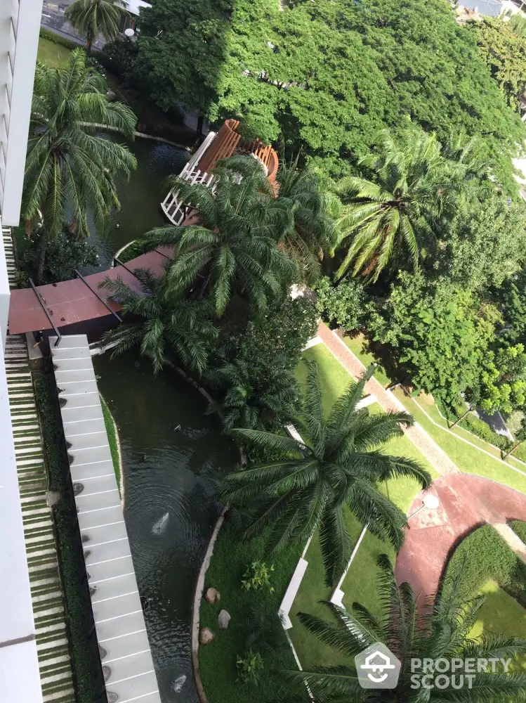 Stunning aerial view of lush garden with palm trees and winding pathways in a luxury residential complex.