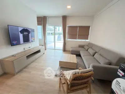 Modern living room with sleek furniture and large window opening to balcony.