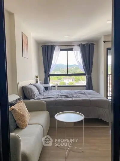Cozy bedroom with scenic view, featuring a comfortable bed, stylish sofa, and large window with curtains.