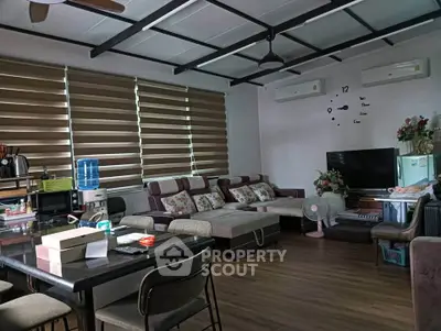 Spacious living room with modern decor and ample natural light, featuring a cozy seating area and dining space.