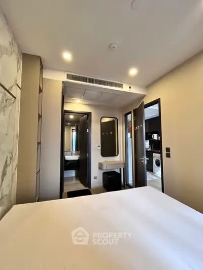 Modern bedroom with ensuite bathroom and laundry area, featuring sleek design and neutral tones.