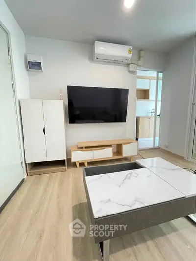 Modern living room with sleek furniture and wall-mounted TV, featuring a minimalist design and light wood flooring.