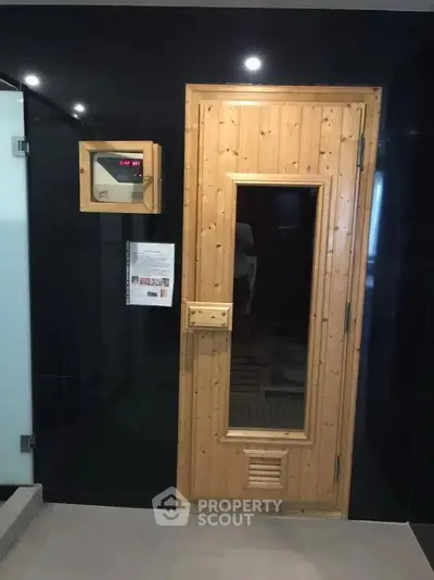 Luxurious sauna room with wooden door and modern control panel in upscale property.