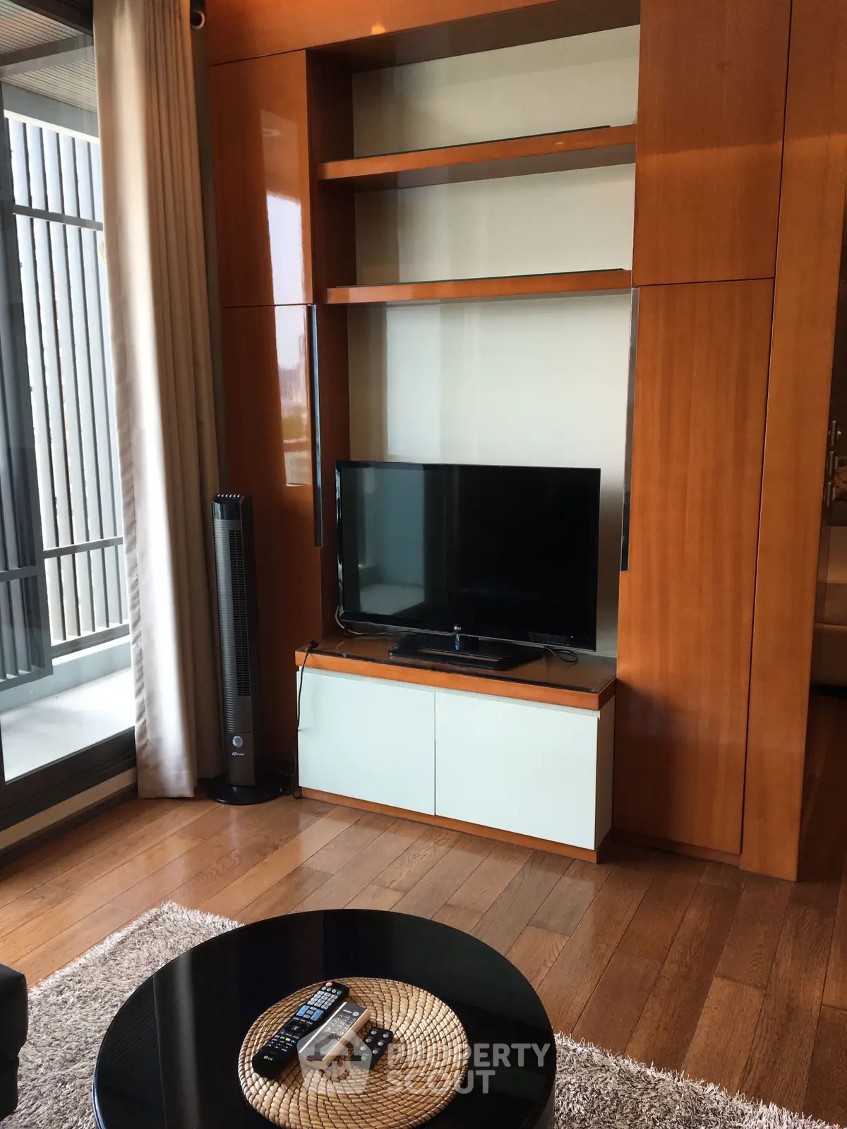 Modern living room with sleek TV stand and balcony view, featuring elegant wooden flooring and contemporary decor.