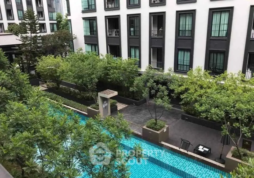 Luxurious residential building with lush garden and sparkling pool view.
