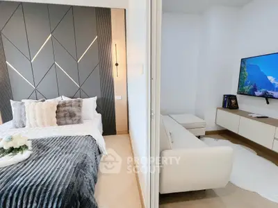 Modern bedroom with stylish decor and adjacent cozy living area featuring a wall-mounted TV.