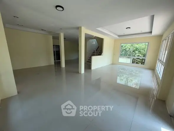 Spacious open-plan living area with large windows and glossy tiled floors.