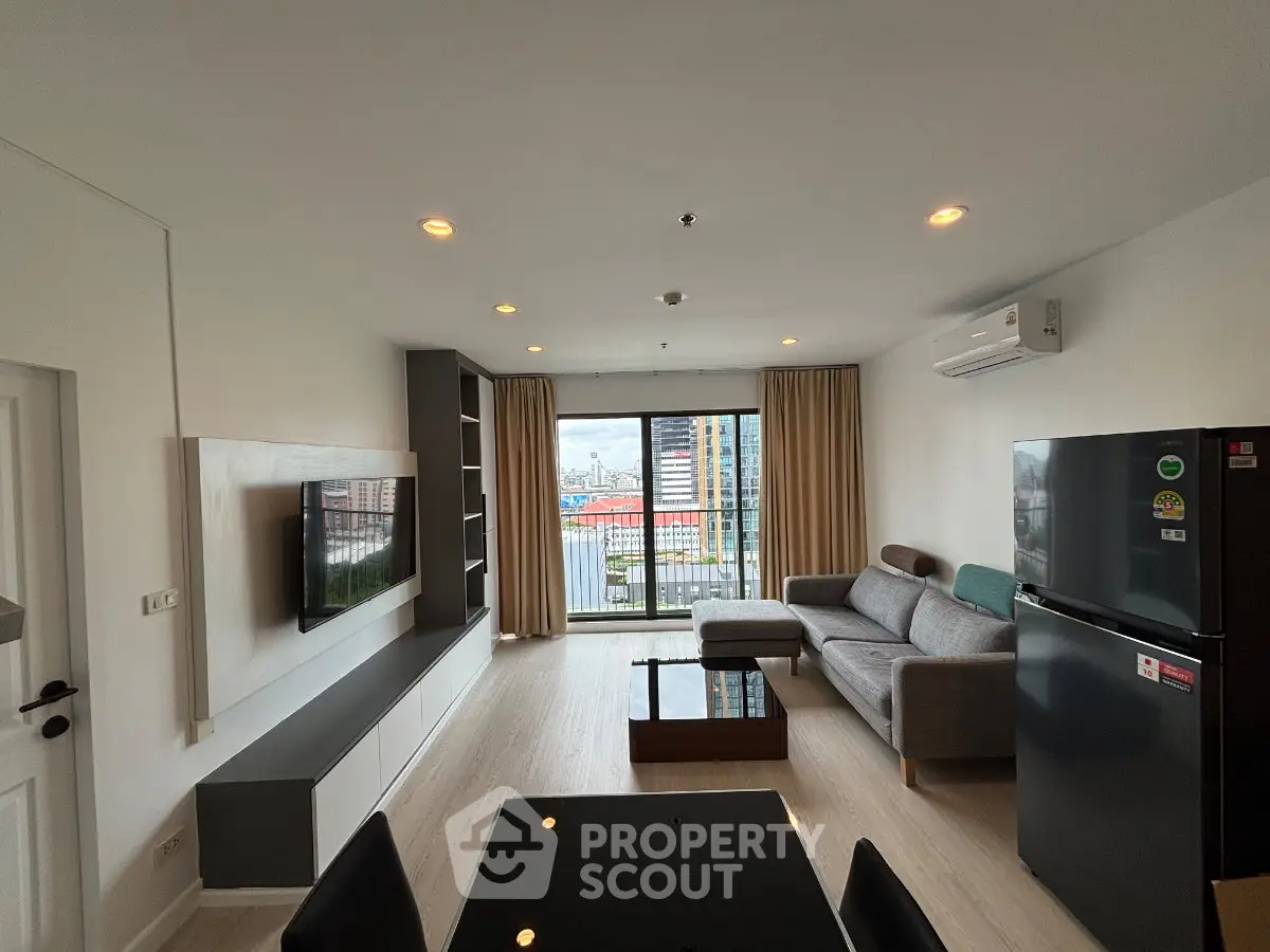 Modern living room with city view, featuring sleek furniture and large windows for natural light.