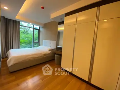 Spacious modern bedroom with large window and elegant wooden flooring