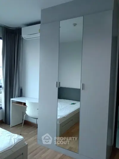 Modern bedroom with mirrored wardrobe and study desk, featuring sleek design and natural light.