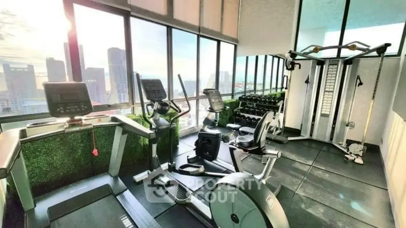 Modern gym with city view, featuring treadmills and weight machines in a high-rise building.
