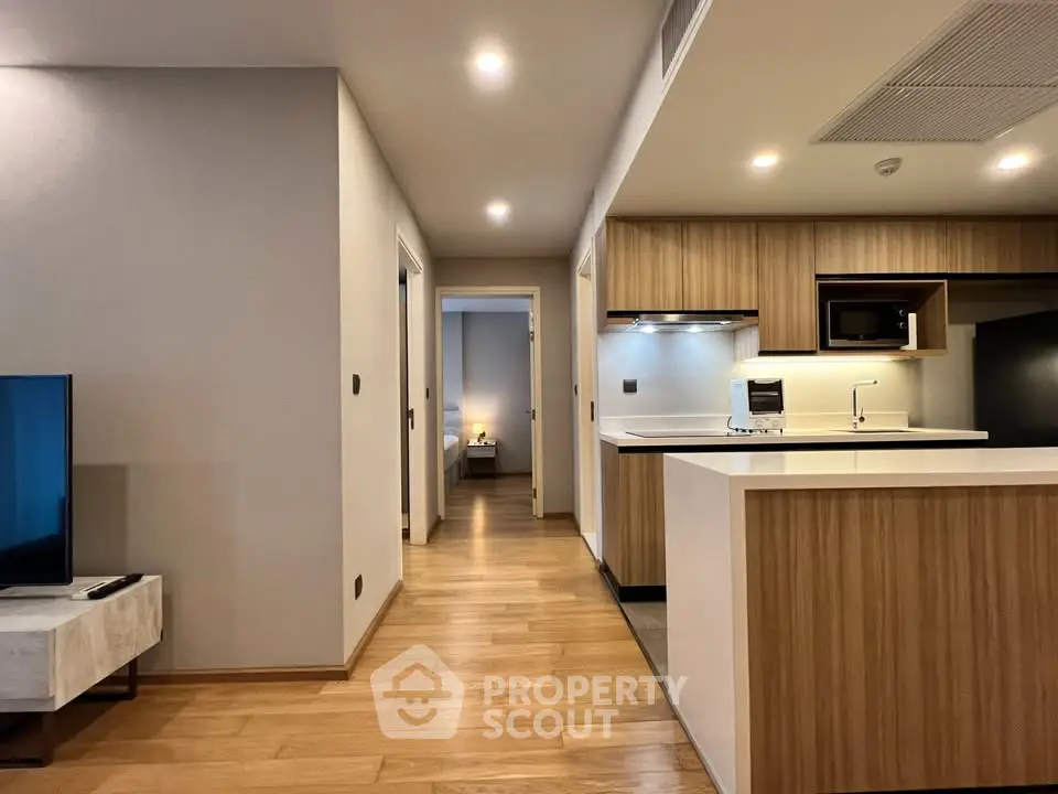 Modern open-plan kitchen and hallway leading to a cozy bedroom in a stylish apartment.