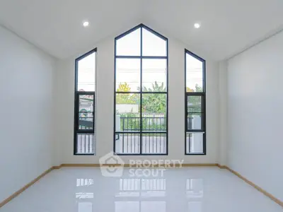 Spacious room with large windows and high ceiling, perfect for natural light.