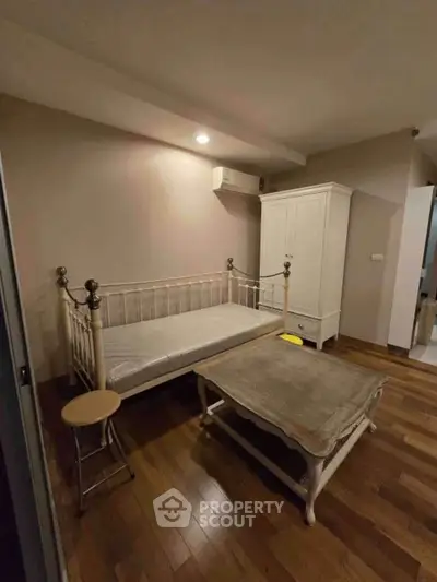 Cozy bedroom with wooden flooring and classic furniture, perfect for relaxation.