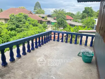 Spacious balcony with scenic view of lush greenery and rooftops, perfect for relaxation.